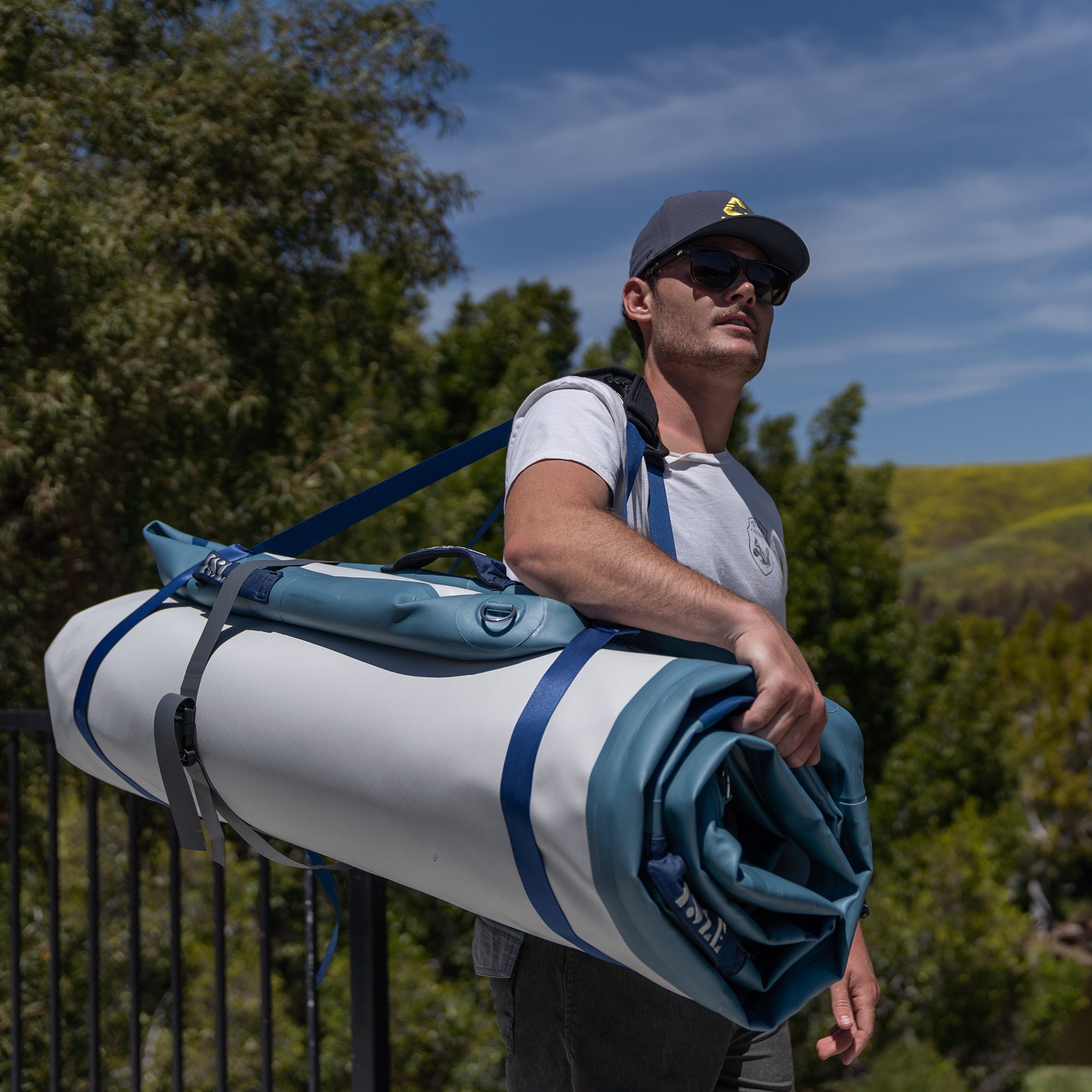 Man Carrying The Base Camp Blue Inflatable Dock With The Minimalistic Carry System