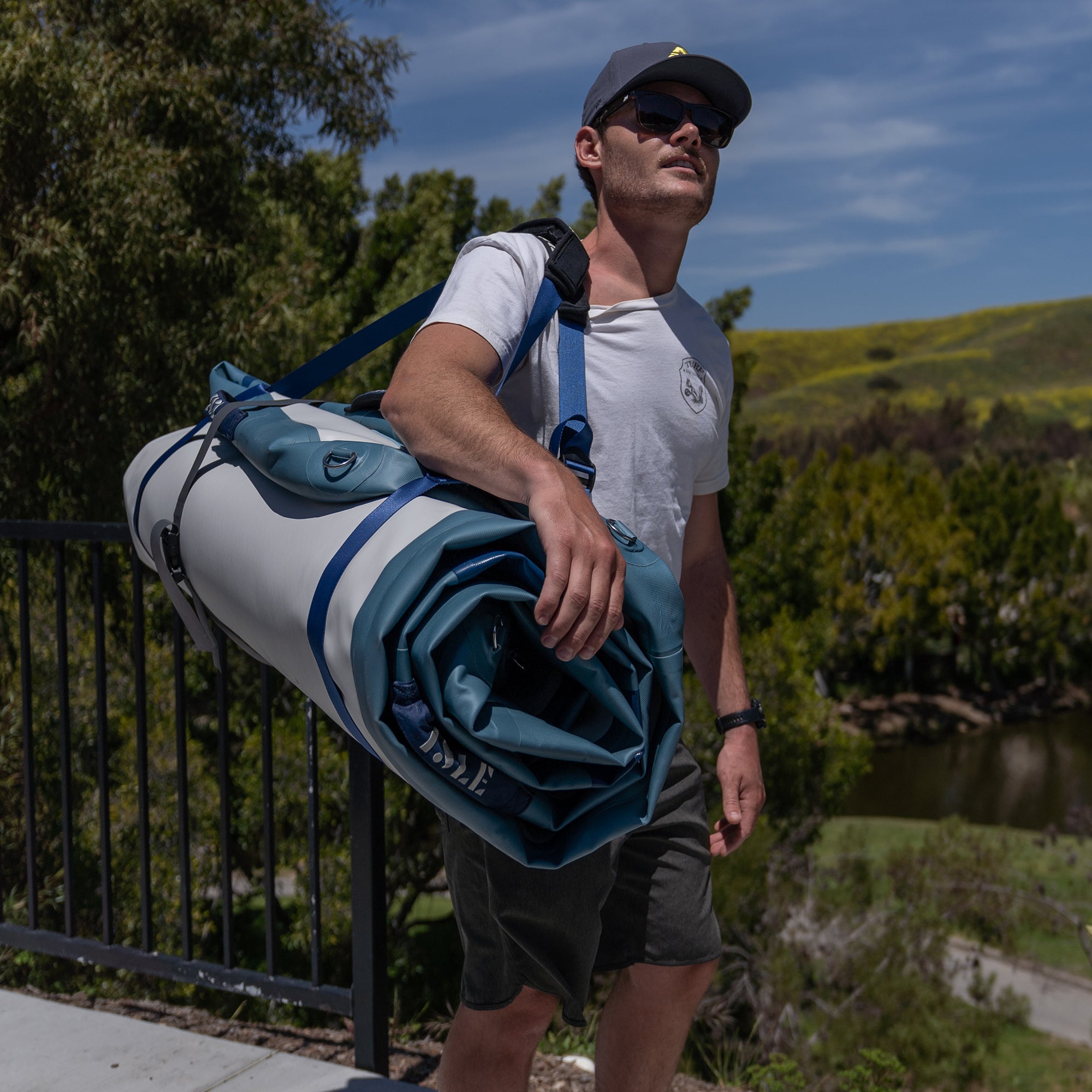 Man Carrying The Base Camp Blue Inflatable Dock With The Minimalistic Carry System