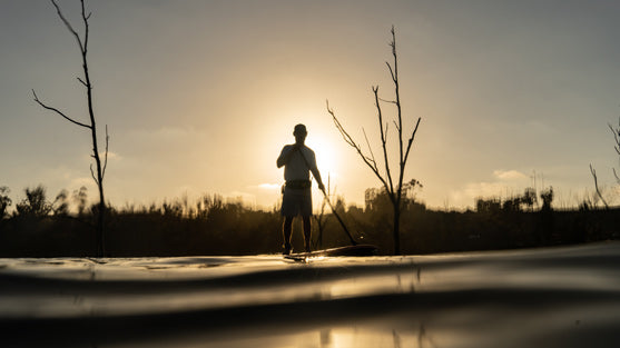 man paddling during sunset