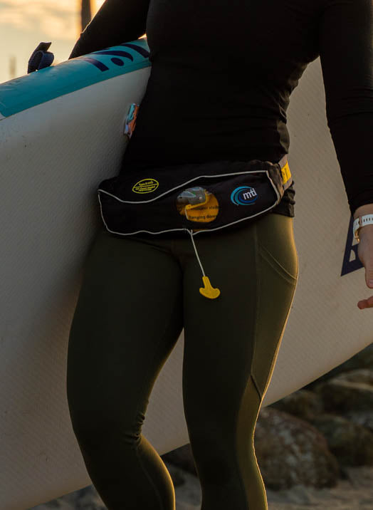 Person Wearing The MTI Fluid 2.0 Inflatable Belt Pack Life Jacket While Carrying Their Paddle Board