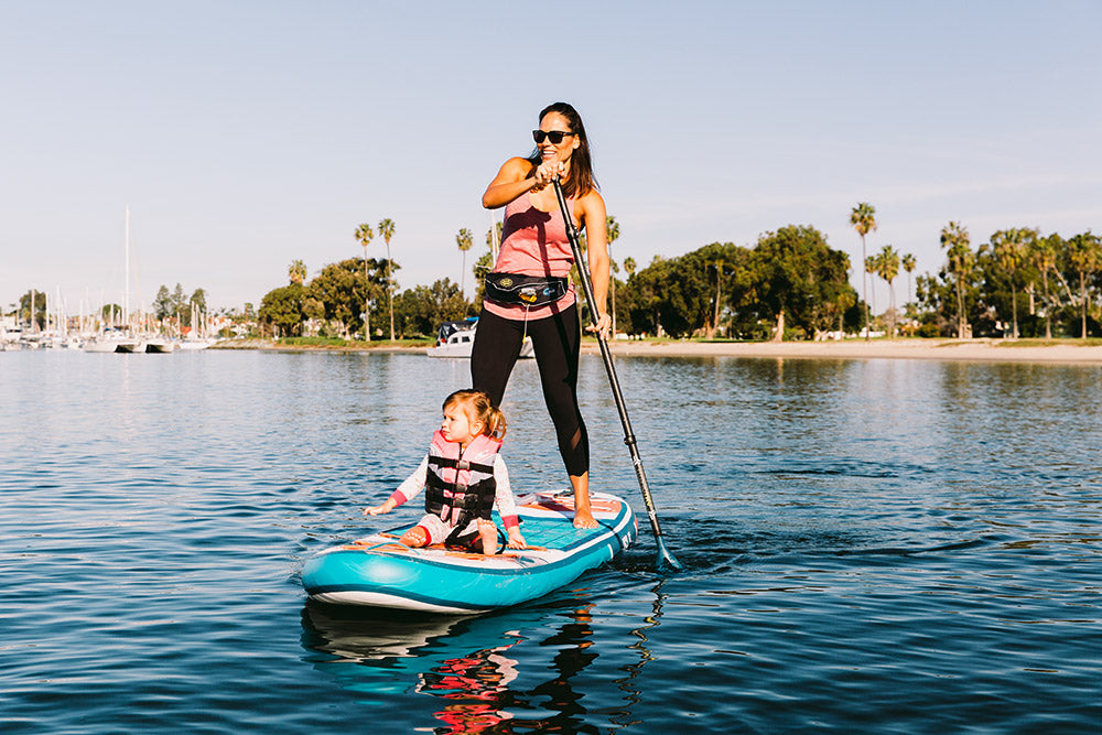 Mother & Daughter Wearing The MTI Fluid 2.0 Inflatable Belt Pack Life Jacket While Paddle Boarding