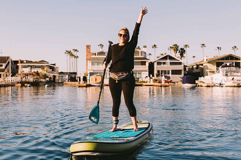 Women Wearing The MTI Fluid 2.0 Inflatable Belt Pack Life Jacket While Paddle Boarding